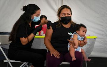 劳拉·桑切斯(右)抱着她两个月大的儿子莉桑德罗，在加利福尼亚州奥兰治市CalOptima停车场的疫苗诊所，从注册护士诺琳·诺布尔扎那里接受一剂辉瑞COVID-19疫苗。州长加文·纽森于2021年8月31日周二宣布，加州80%以上的人有资格接种冠状病毒疫苗