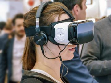 一名女子戴着虚拟现实耳机。＂width=