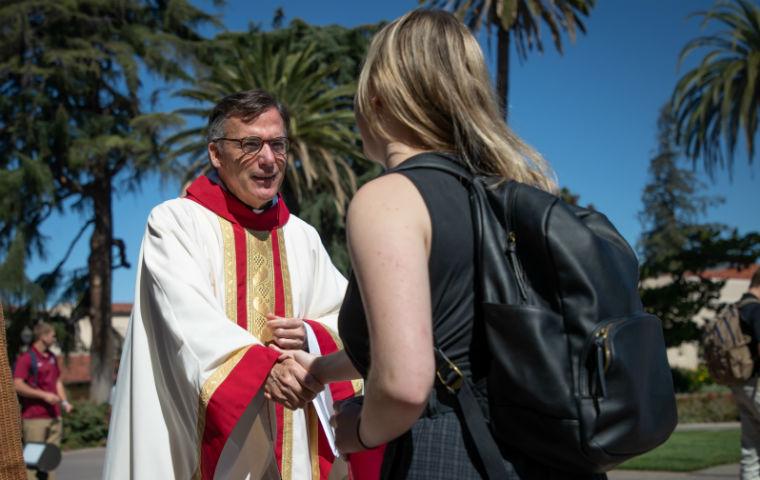神父奥布莱恩在牧师服装与女学生握手，从学生后面看到