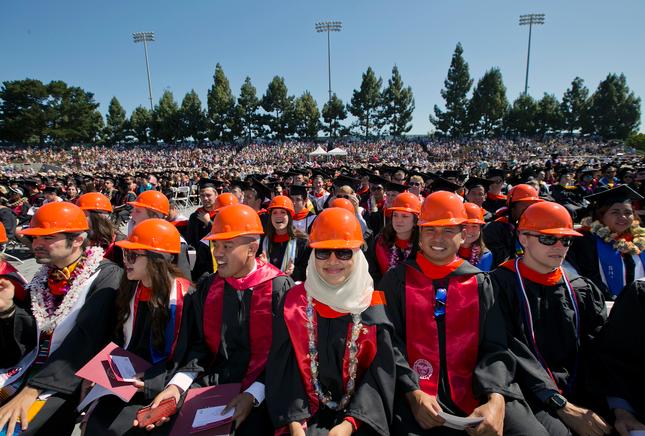 土木工程的学生与他们的礼服穿橙色安全帽帽在本科生毕业典礼
